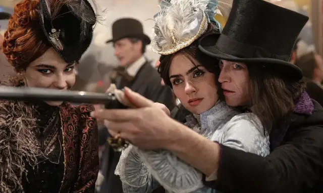 Una donna con un cappello piumato punta una pistola, protetta da un uomo con un cilindro. Un'altra donna con un cappello decorato sorride. Un momento intenso da "Dracula a love tale".