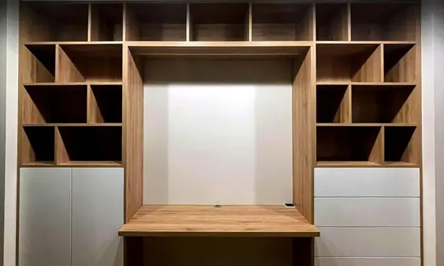 Einbauwand mit Schreibtisch und vielen Fächern. Weiße Schubladen bieten unsichtbaren Stauraum für Ordnung.