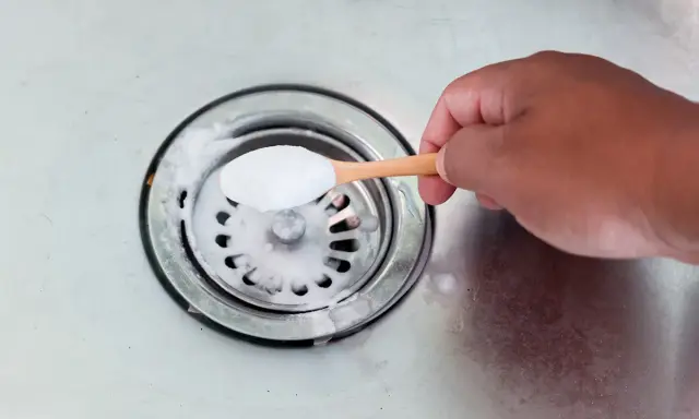 Maintenant, je vais aider à déboucher le siphon. Une cuillère de bicarbonate de soude est versée dans l'évier.