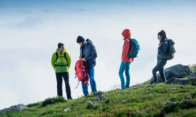 Czterech turystów w górskim krajobrazie, przygotowujących się do wyprawy. To właśnie jest co to trekking – przygoda i odkrywanie.
