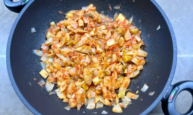 Finocchi in padella, tagliati a pezzi e cotti con pomodoro e spezie, emanano un profumo invitante.