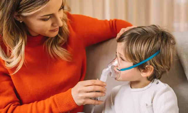 Mamma assiste il bambino con un inalatore per alleviare il broncospasmo.