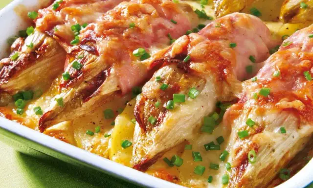 Gebackener Chicorée in Schinken gewickelt, überbacken mit Käse und Kartoffeln. Ein köstliches Gericht für alle, die Rezepte mit Schinken lieben.