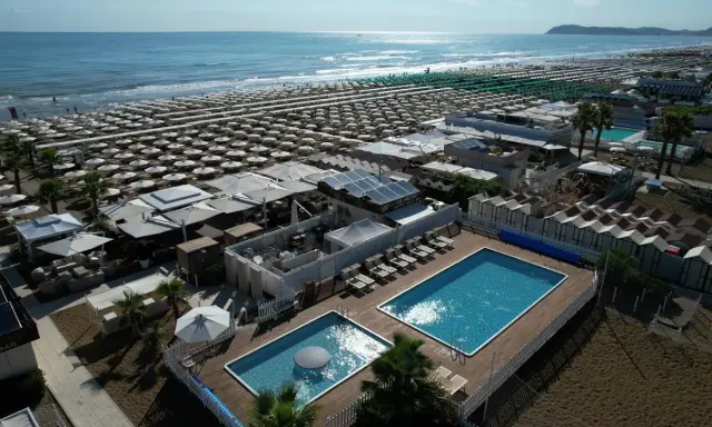 Vista aerea della spiaggia Le Palme Riccione con ombrelloni, piscine e cabine.
