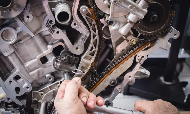 Mechanik pracuje przy rozrządzie silnika. Wymiana poduszki silnika może być konieczna, gdy pojawią się objawy takie jak wibracje.