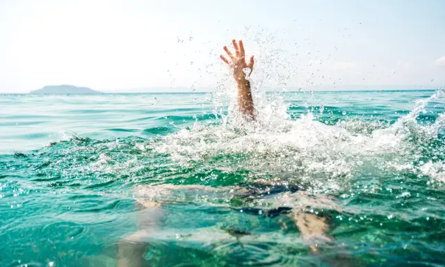 Main d'une personne émergeant de l'eau, éclaboussures vives. Un appel à l'aide pour sauver quelqu'un de la noyade.