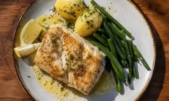 En tallrik med saftig torskrygg, kokt potatis, gröna bönor och citronklyftor. Perfekt för ett enkelt torskrygg recept.