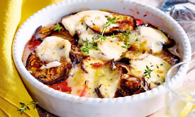 Ein köstlicher Auberginen Tomaten Auflauf mit geschmolzenem Käse und frischen Kräutern, bereit zum Genießen.