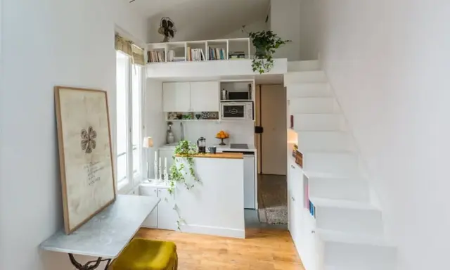 Un petit appartement optimisé avec un coin cuisine, un bureau escamotable et un escalier menant à une mezzanine. Idéal pour un **DIY rangement** créatif.