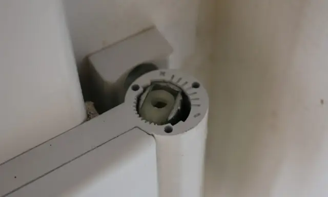 Mécanisme de réglage gond porte, avec une molette crantée et un axe carré pour ajuster la position.