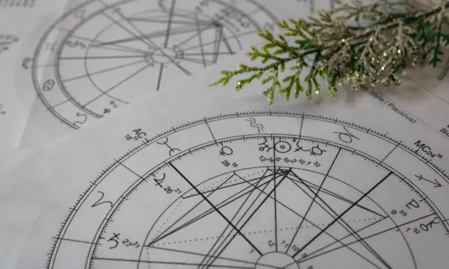 Kosmogram co to? Na papierze widnieją skomplikowane wykresy astrologiczne, pełne symboli planet i znaków zodiaku, przypominające mapę nieba.
