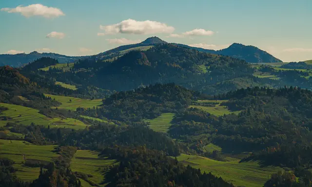 Wysokie Pieniny w jesiennej szacie, zielone pola i lasy tworzą malowniczy krajobraz.