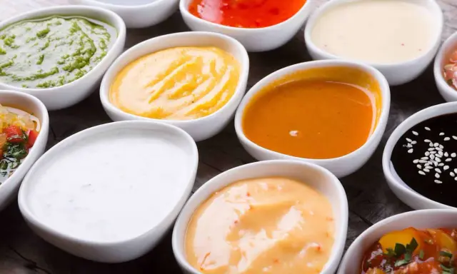 Assortiment de sauces pour raclette : verte, jaune, orange, blanche, rouge, noire. Un délice pour accompagner votre fromage fondu.