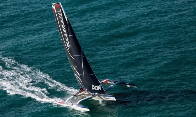 Le trimaran Maserati, skippé par Giovanni Soldini, fend les vagues bleues, laissant une traînée d'écume.