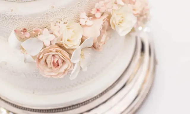 Elegancki tort na 150 osób, ozdobiony delikatnymi koronkami i pastelowymi kwiatami z masy cukrowej. Idealny na wielkie przyjęcie.