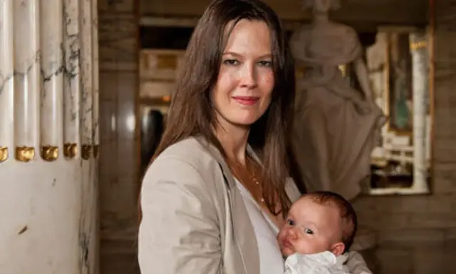 Elin Klinga med sitt barn. En vacker mamma med sitt nyfödda barn i famnen, omgivna av klassisk arkitektur.
