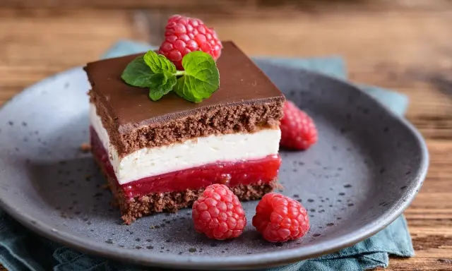Pyszne ciasto Balladyna z malinami i bitą śmietaną, polane czekoladą.