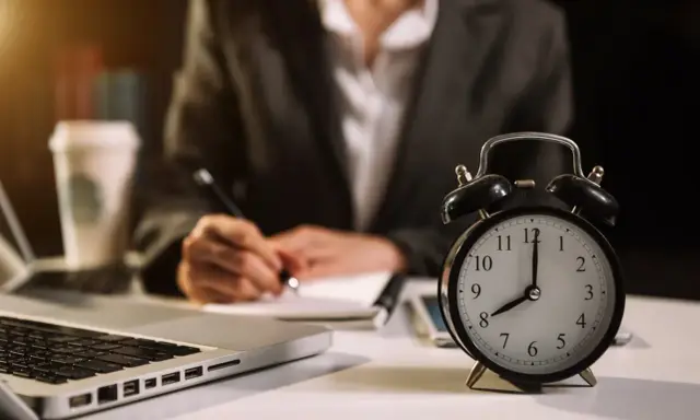 Zegar pokazuje 8:00. Osoba pisze notatki, pracując w grudzień dni pracujące.