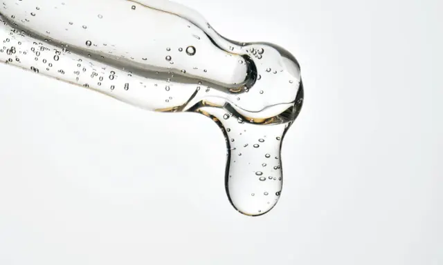 Kwas salicylowy działanie: przejrzysty żel z pęcherzykami powietrza spływa z pipety, obiecując czystą i odświeżoną skórę.