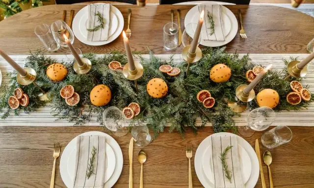 Vackert dukat julbord med granris, apelsiner med nejlikor, torkade apelsinskivor och ljus. En perfekt inspiration för att dekorera julbordet.