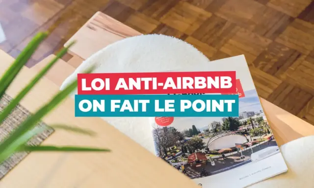 Un magazine sur la **loi Airbnb** est posé sur un meuble en bois. Le titre "Loi anti-Airbnb, on fait le point" est bien visible.