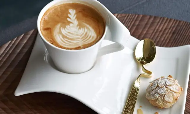 Ein Latte Macchiato mit schönem Milchschaum-Muster und ein Mandelgebäck, perfekt zum wiener Zubereiten.