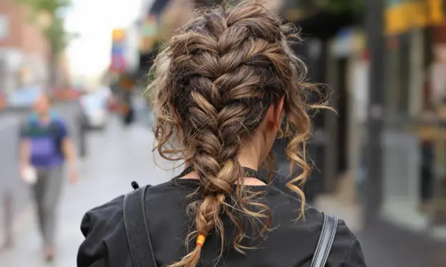 Eine halboffen hochsteckfrisur mit geflochtenen Strähnen und einzelnen locken, die lässig herabhängen.