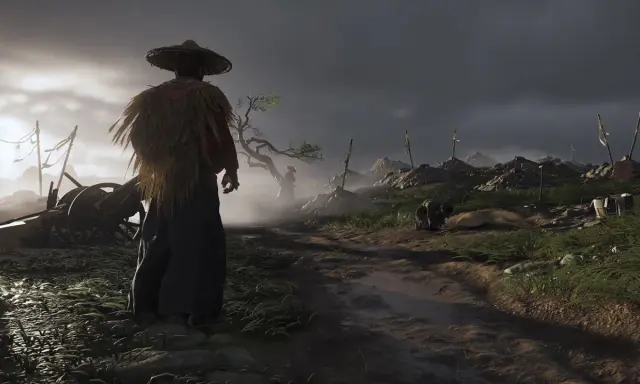 Samuraj w słomkowym kapeluszu stoi na poboczu drogi, obserwując pole bitwy z gry Ghost of Tsushima.