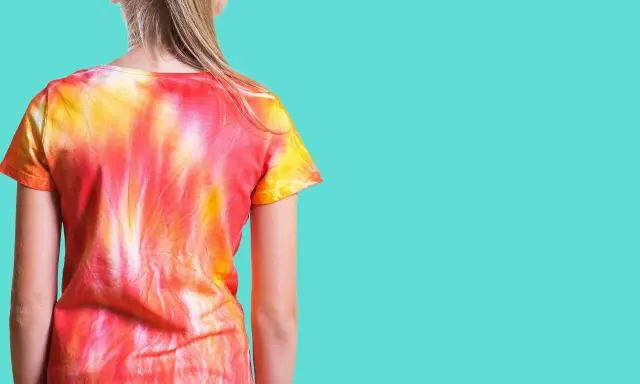 Dziewczynka w koszulce tie dye w odcieniach czerwieni i żółci.