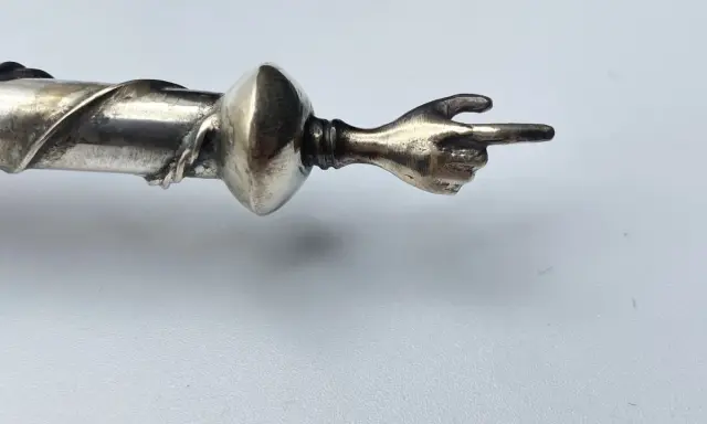 Manico in argento 325, cosa significa? Un dettaglio di un oggetto con una mano che indica.
