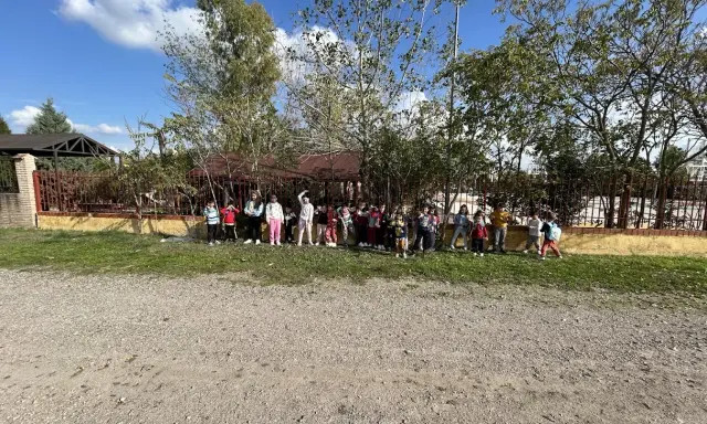 Niños y niñas posan en la granja escuela La Chopera, disfrutando de un día soleado rodeados de árboles y vegetación.