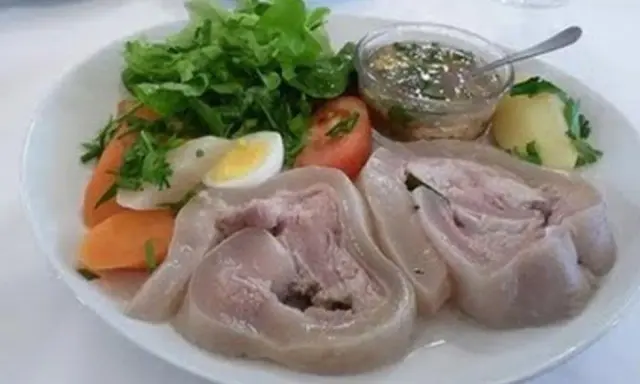 Tête de veau en cocotte, servie avec des légumes, un œuf dur et une sauce vinaigrette. Un plat traditionnel savoureux.