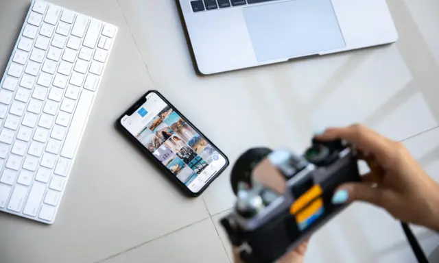 Aparat fotograficzny służy do uwieczniania chwil. Obok klawiatury, telefonu z Instagramem i laptopa, jest gotowy do pracy.