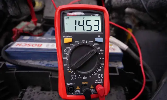Multimetr pokazuje 14.53V, sprawdzając regulator napiecia alternatora przy akumulatorze Bosch.