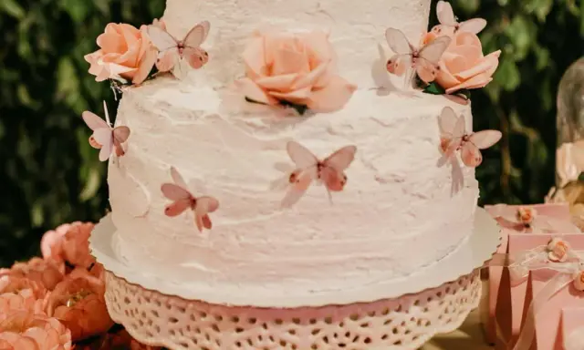 Gâteau à étages décoré de roses et de papillons, recouvert d'une délicate crème au beurre.