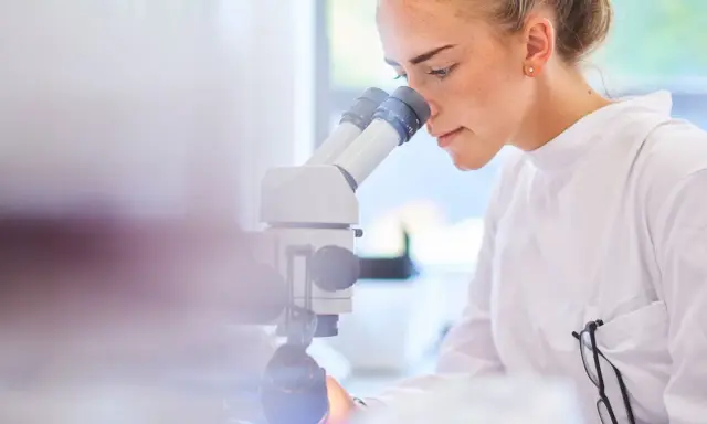 Ricerca scientifica per capire cos'è il sarcoma. Giovane scienziata al microscopio.