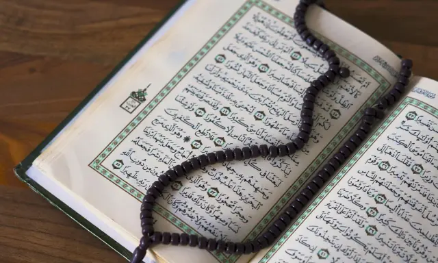 Ein offener Koran mit einer Gebetskette liegt auf einem Holztisch. Der Koran ist ein heiliges Buch im Islam, das von Muslimen auf der ganzen Welt verehrt wird. Israel ist ein Land im Nahen Osten, das eine reiche Geschichte und eine vielfältige Bevölker...