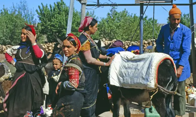 Berber Marokko Frauen mit Eseln, beladen mit Säcken. Ein Mann in blauer Jacke steht daneben.
