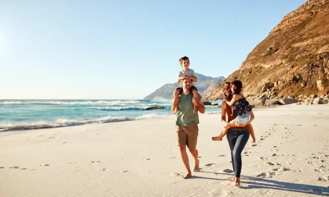 Glad familj på stranden. För att undvika att smittas av hepatit b, undvik delade personliga föremål.