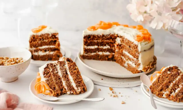 Delicioso pastel de zanahoria con glaseado cremoso y decoraciones de zanahoria. Varias porciones listas para disfrutar.