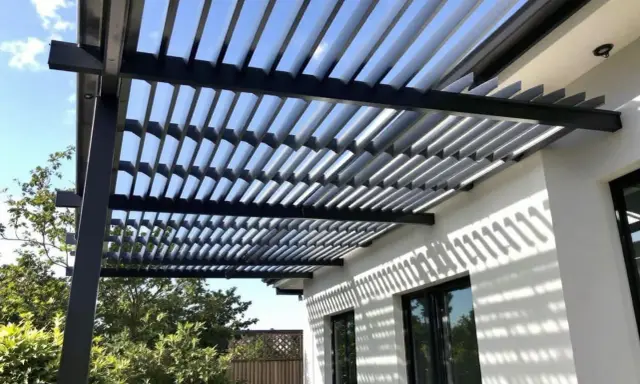 Ombre et lumière sur une maison moderne grâce à l'orientation des lames d'une pergola bioclimatique.