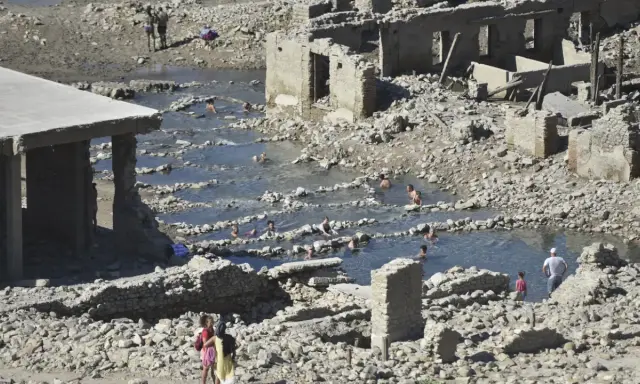 Ruinas de las termas de Yesa, con gente bañándose en las piscinas naturales formadas entre los escombros.