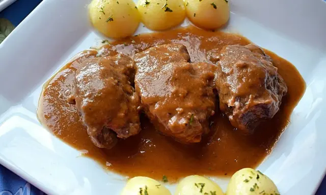 Carrilleras al vino tinto, tiernas y jugosas, bañadas en una rica salsa, acompañadas de patatas cocidas.