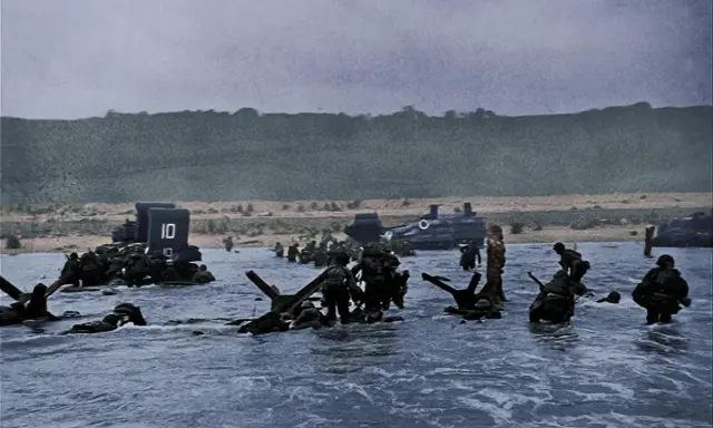 Soldati avanzano nell'acqua durante lo sbarco in Normandia. Un fotografo immortalò questo momento storico.