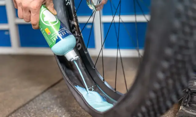 Flüssigkeit wird in einen MTB-Reifen gegossen, um ihn für den Tubeless-Betrieb vorzubereiten. Das ist ein wichtiger Schritt beim MTB Reifen wechseln.