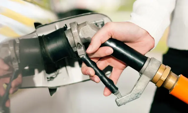Dłoń trzymająca pistolet do tankowania, gotowa do nalania gazu do diesla.