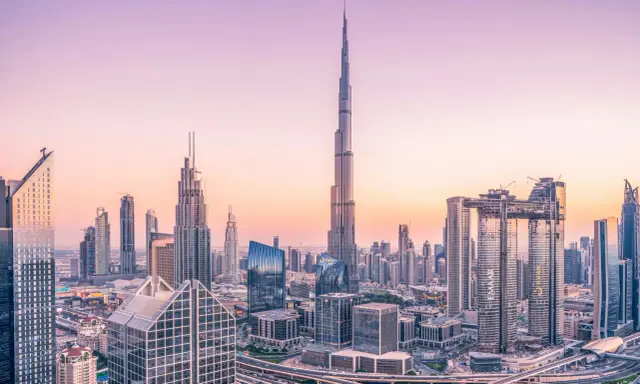 Dubaj o zachodzie słońca, z dominującym Burdż Chalifa, najwyższym budynkiem świata, otoczonym nowoczesnymi wieżowcami i autostradami.