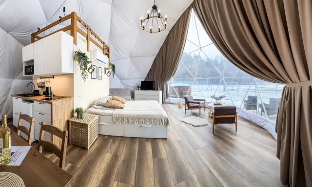 Przytulny glamping w Wielkopolsce: domek z aneksem kuchennym, wygodnym łóżkiem i widokiem na zimowy krajobraz.