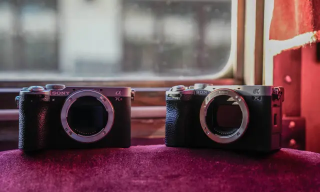 Dwa aparaty Sony Alpha, jeden a7c i drugi a7CR, leżą obok siebie na aksamitnym materiale.