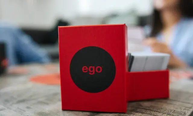 Czerwone pudełko gry "ego" z czarnym kołem i napisem "ego" w środku. Obok stos kart. Czas na ego gold pytania!